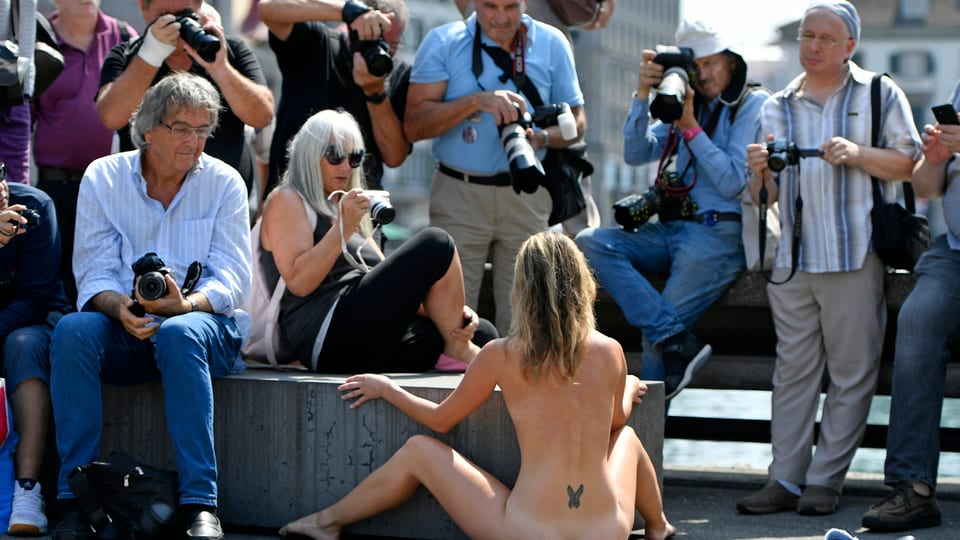 Eine Nacktkünstlerin performt in der Zürcher Innenstadt beobachtet von fotografierenden Männern 