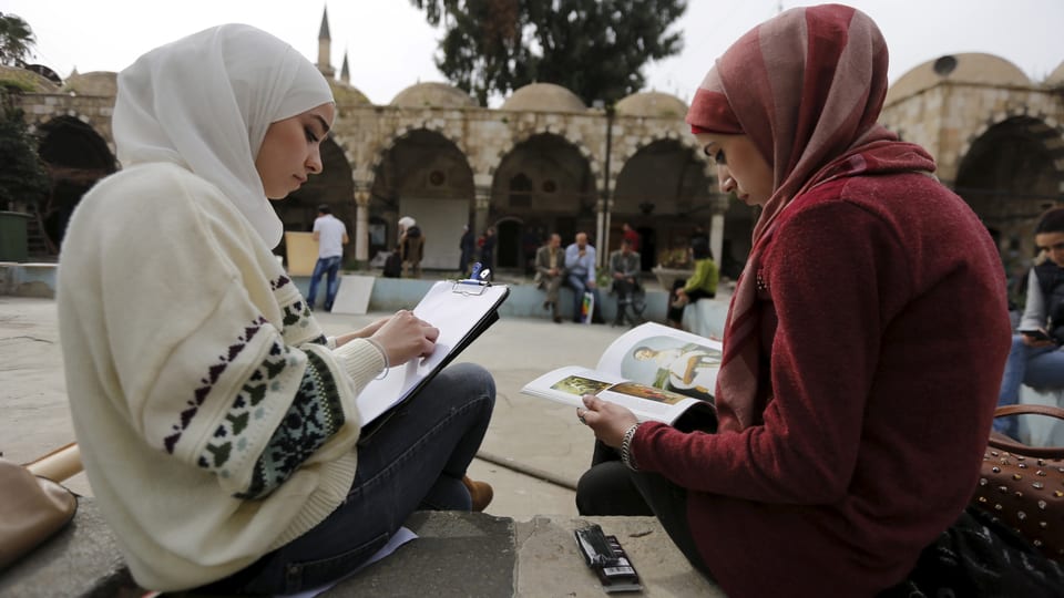 Zwei junge Frauen mit Buch vor einer Moschee in Damaskus. 