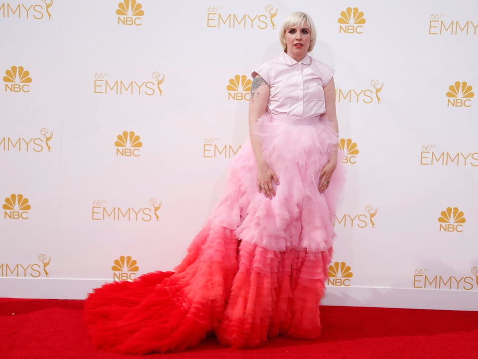 Lena Dunham in rosa-rotem Kleid auf dem roten Teppich der Emmys