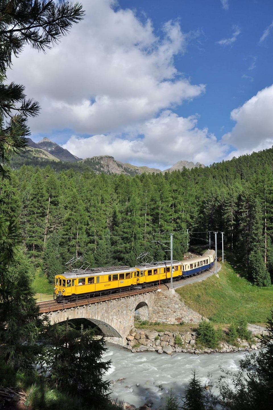 Ein gelber Zug fährt über eine Brücke.