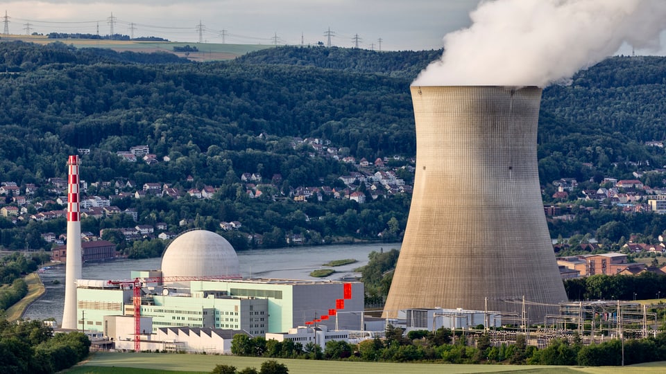 Kühlturm des AKW mit aufsteigendem Dampf. Dahinter der Rhein.