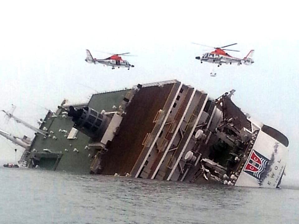 Die «Sewol» liegt mit Schlagseite halb unter Wasser, zwei Rettungshelikopter schweben über dem Schiff
