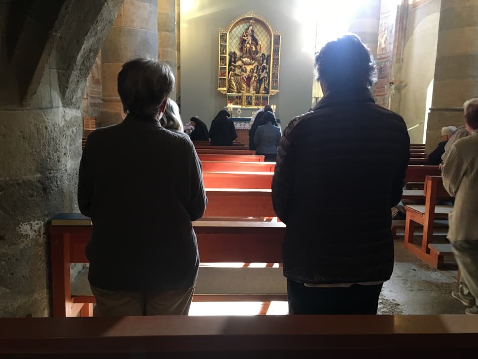 Betende Besucherinnen im Gottesdienst in der Klosterkirche Müstair