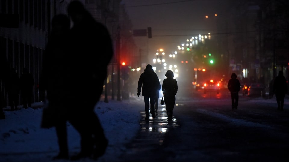 Menschen laufen in Kiew durch nicht beleuchtete, dunkle Strassen.