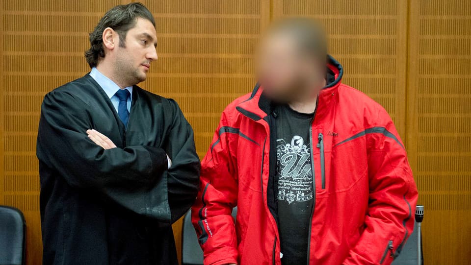 Anwalt Mutlu Gunal (linke Seite), Angeklagter Kreshnik B. mit roter Jacke. Sein Gesicht ist unkenntlich gemacht.
