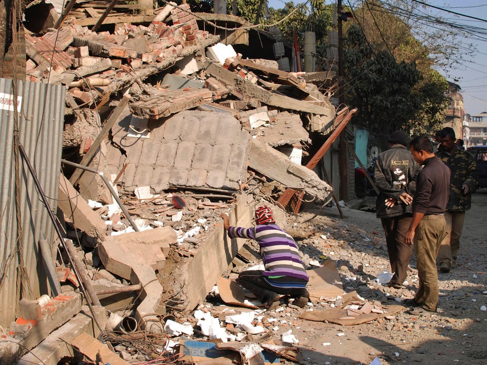 Mann untersuscht Schaden an einem eingestürzten Haus.