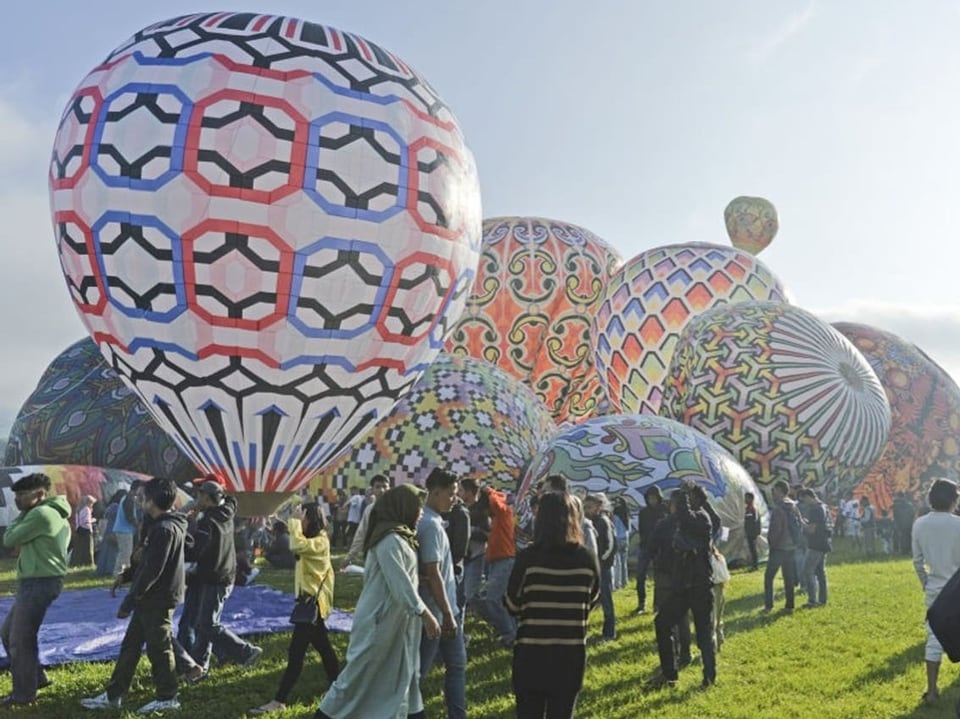 Farbige Heissluftballone werden nebeneinander vorbereitet.