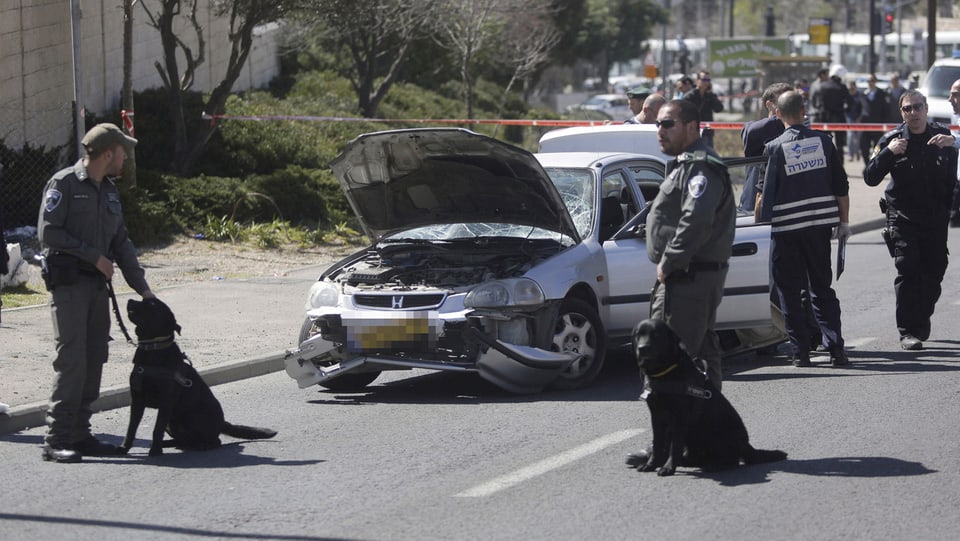 Sicherheitsleute bewachen  das Auto, das in Jerusalem in eine Menschenmenge gefahren ist. 