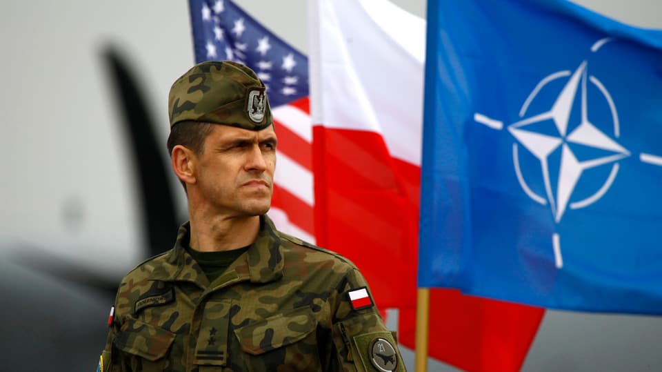 Ein polnischer Soldat vor der polnischen, US- sowie Nato-Flagge