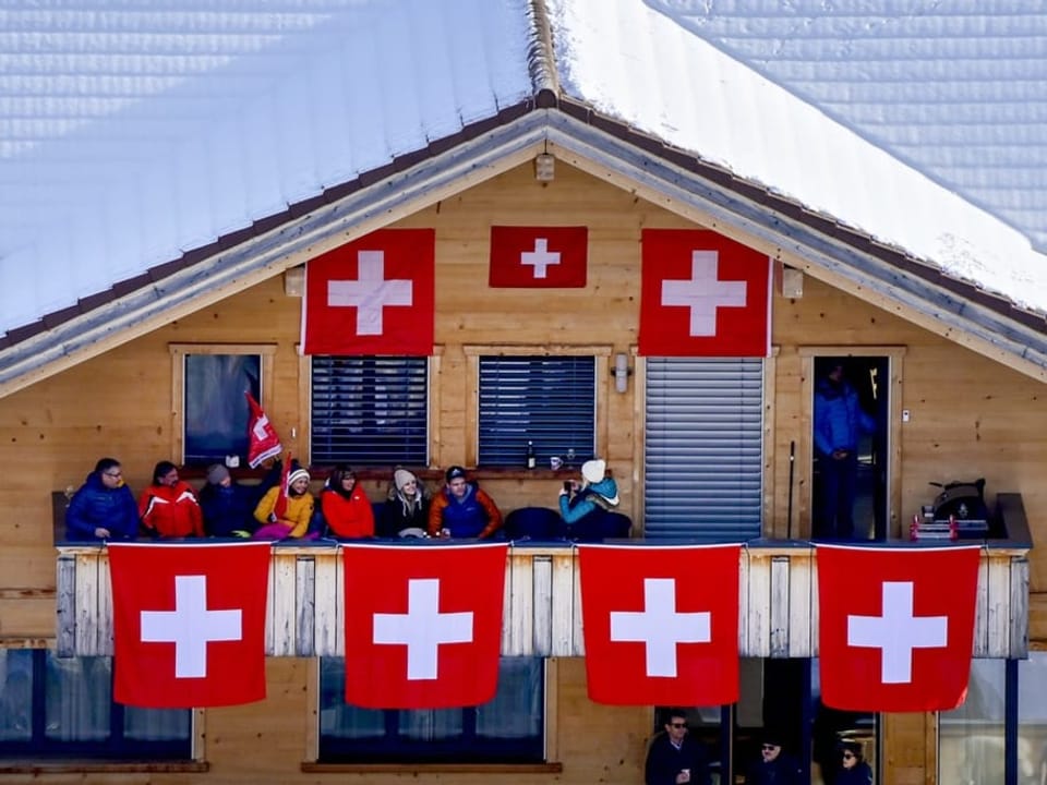 Zaungäste sollen willkommen geheissen werden Schweizer Fahnen an einem Chalet.