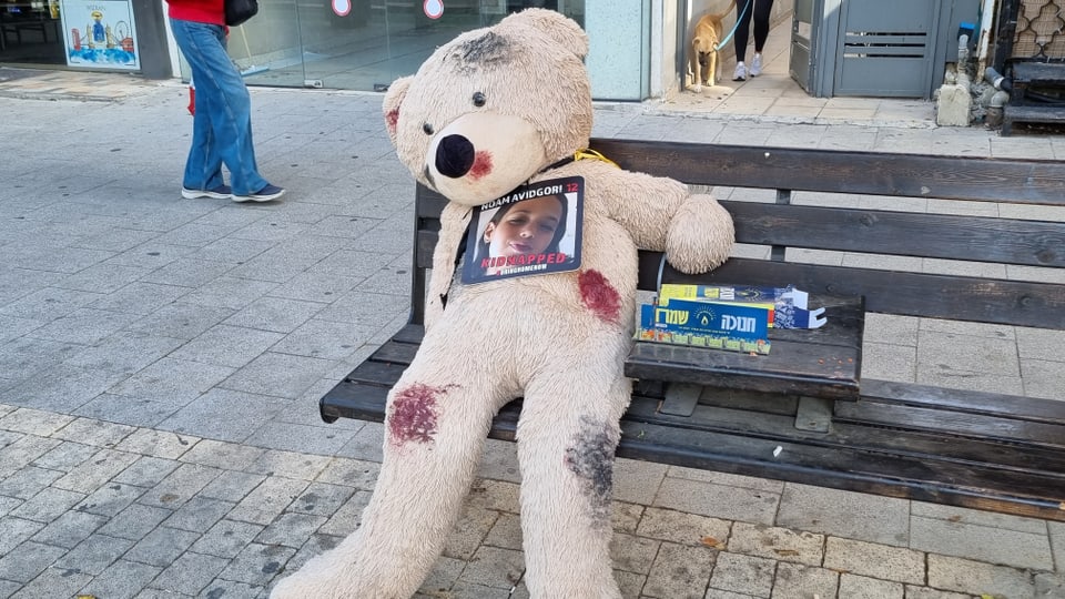 Teddybär mit Foto auf Bank.
