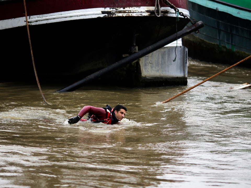Ein Mann im Tauchanzug schwimmt neben einem Boot vorbei.