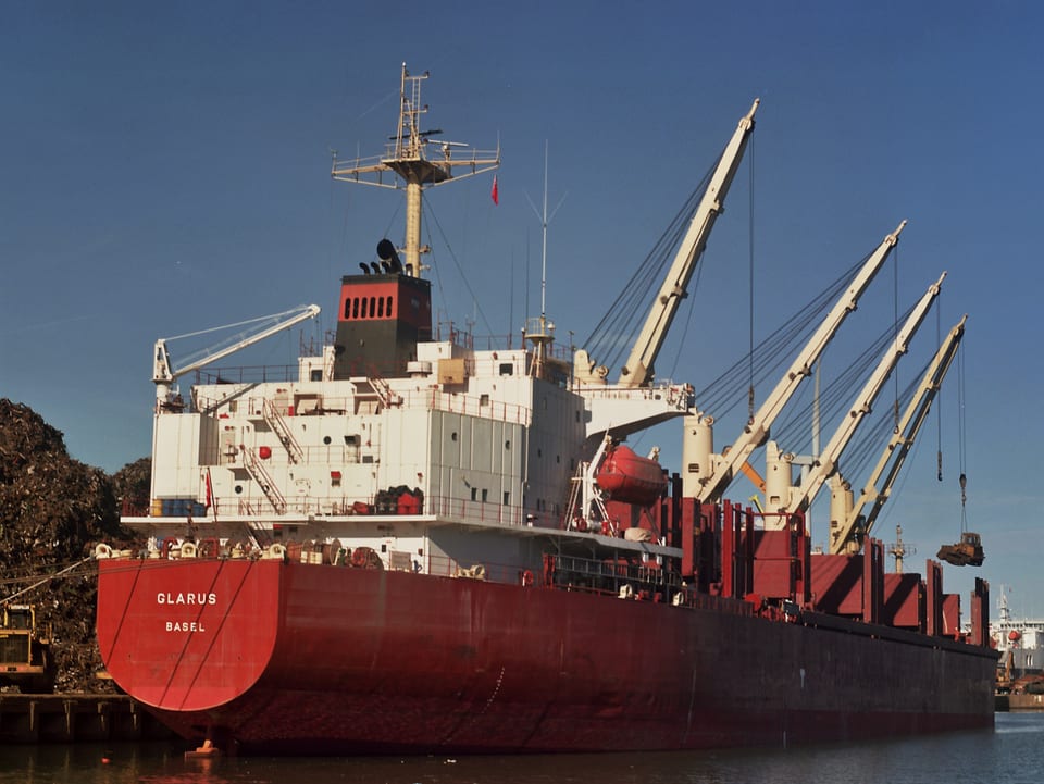 Rot-weisses Frachtschiff mit diversen Kranen, angelegt