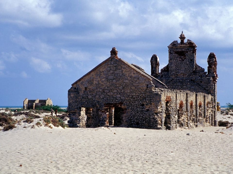 Eine zerstörte Kirche steht am Strand.