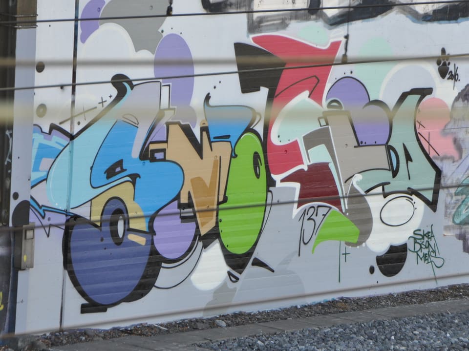 Ein Graffiti auf einer grauen Wand.