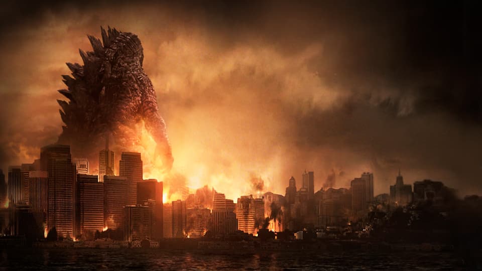 Godzilla guckt auf eine brennende Stadt runter.