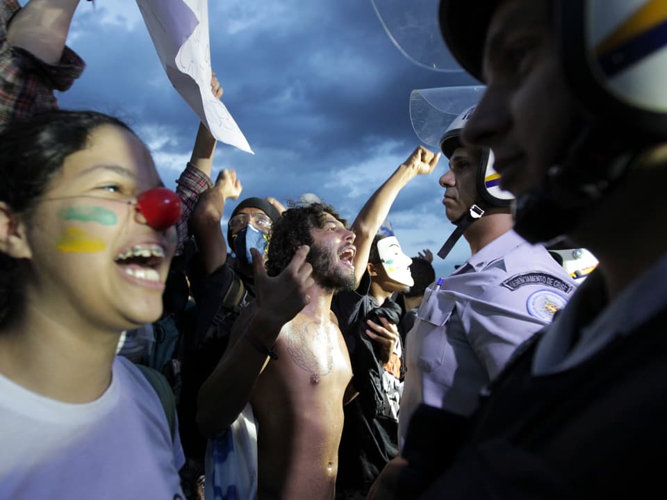 Demonstranten, darunter ein als Clown geschminktes Mädchen, von Angesicht zu Angesicht mit Polizisten.