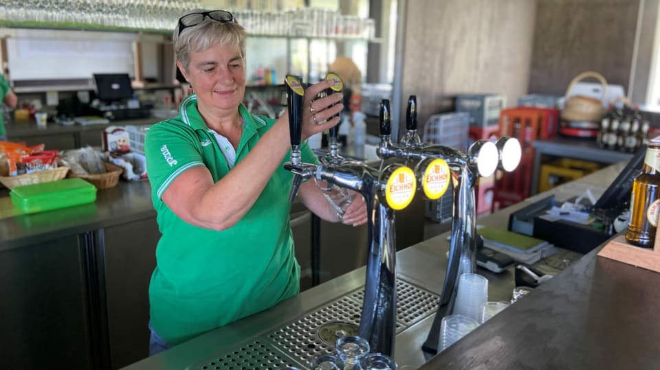 Eine Frau zapft am Tresen ein Bier.