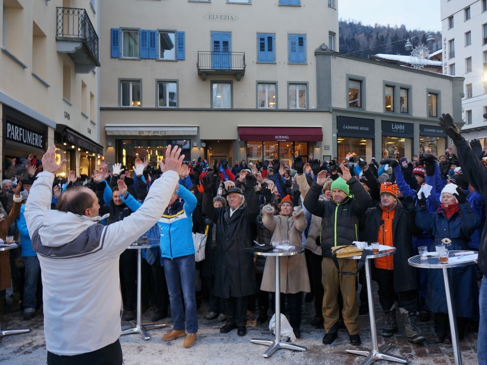 Gian Gilli (Leiter «Olympische Winterspiele Graubünden») hält in der Zwischenzeit mit Turnübungen die Gäste und Zuschauer warm. 