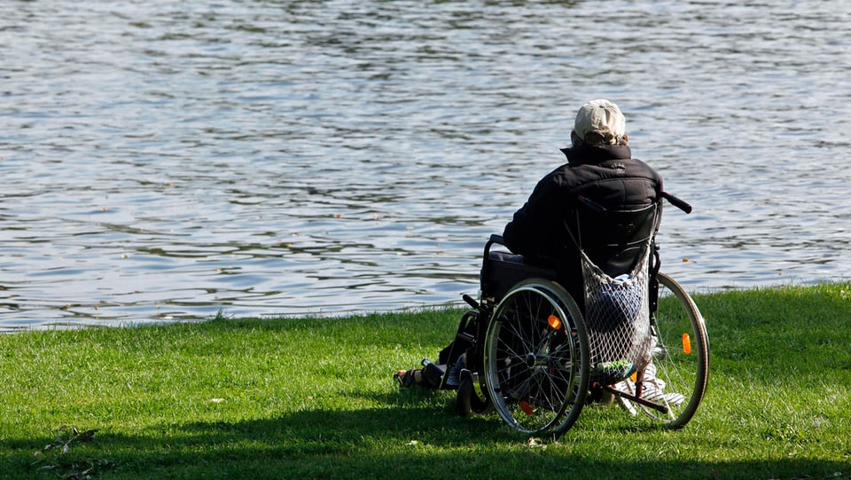 Ein Mann in einem Rollstuhl an einem Ufer.