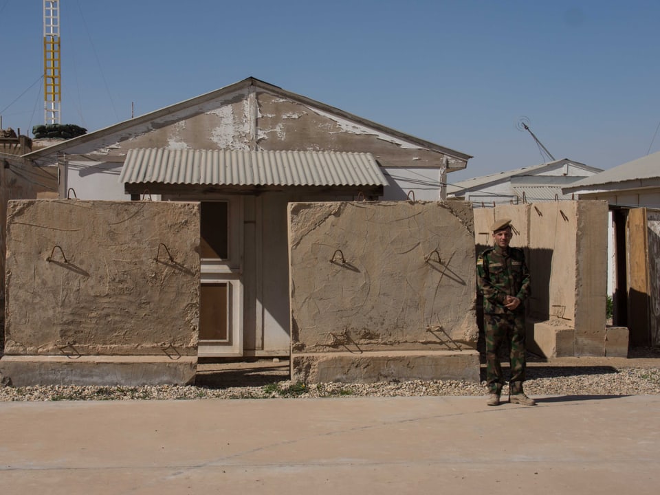 Ein Mann in Uniform steht vor verlassenen Häusern. 