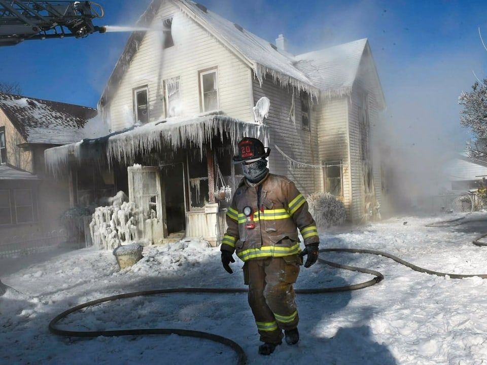 Feuerwehrmann vor vereistem Haus