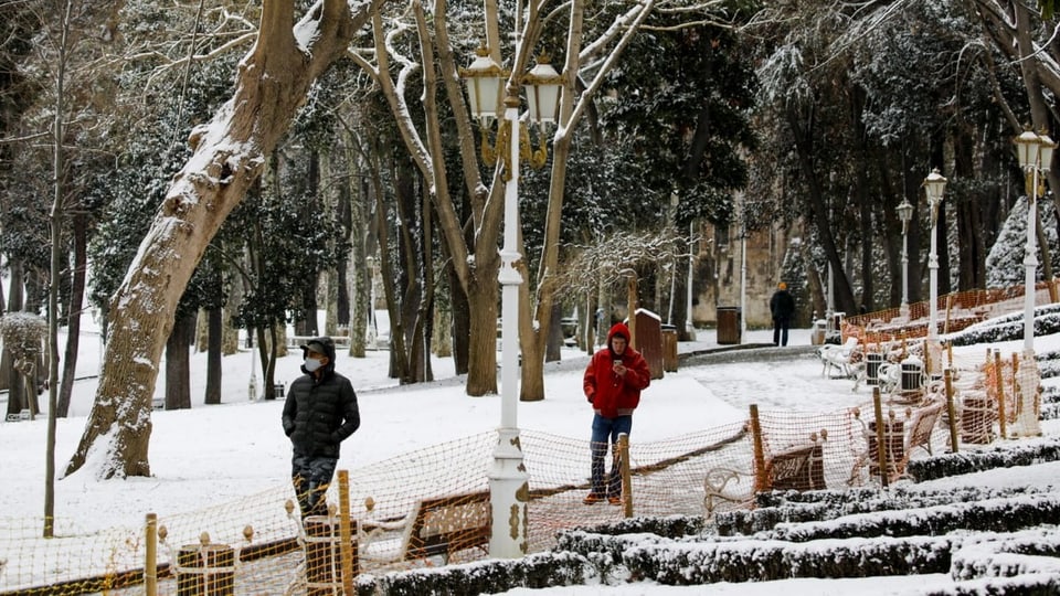 Bürger von Istanbul spazieren in einem verschneiten Park. 