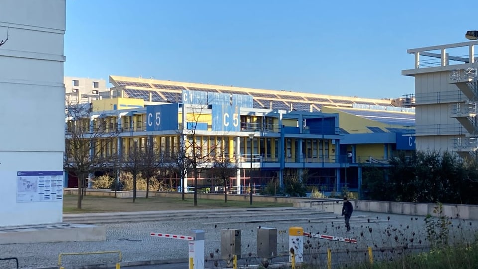 Ein Universitätsgebäude, auf den Dächern viele Solaranlagen