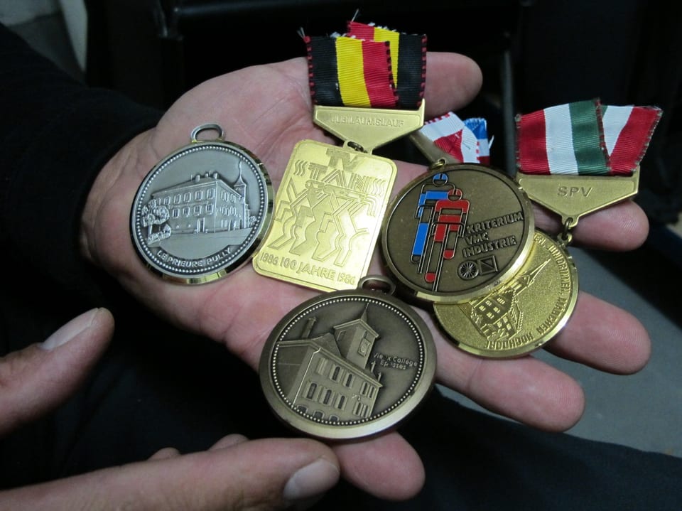 Eine Hand voller Medaillen mit abgeschnittenen Bändeln.