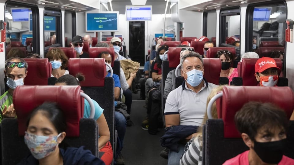 Passagiere mit Maske sitzen in einem voll besetzen Zugabteil der Jungfraubahnen.