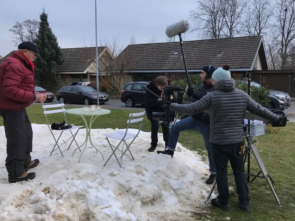 Eine Filmcrew filmt einen Mann auf einer Schneedecke