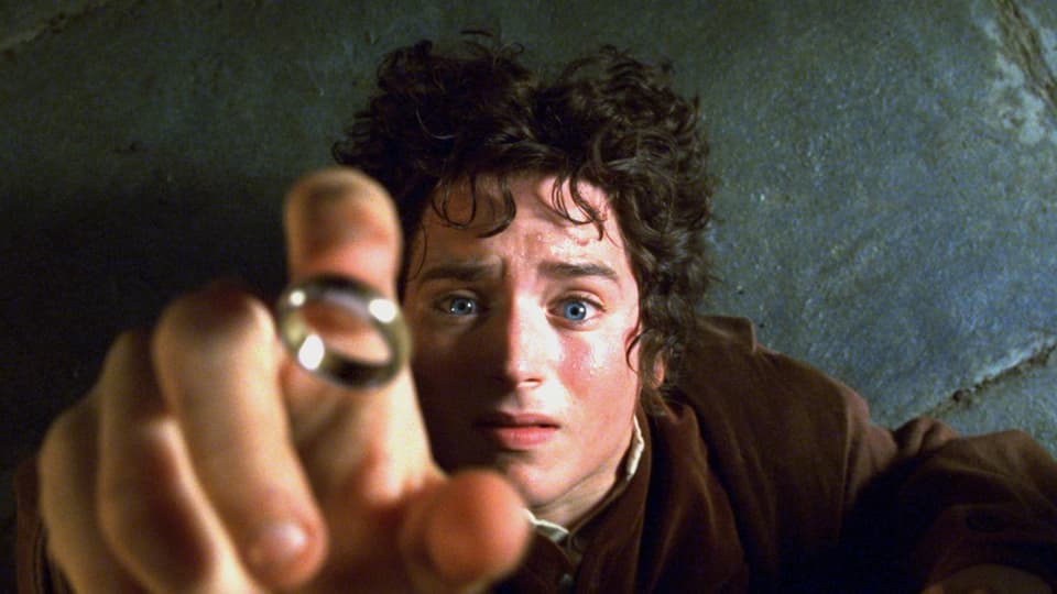 Frodo liegt auf dem Boden und reckt seinen Arm nach dem Ring