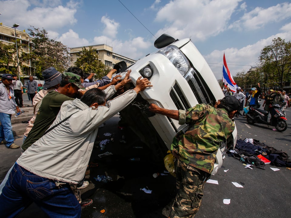 Demonstranten kippen ein Polizeiauto um
