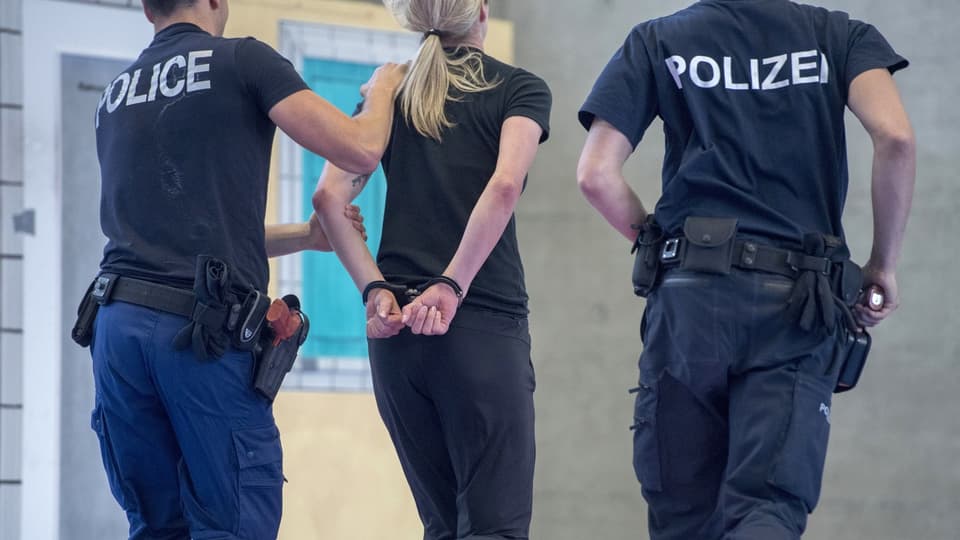 Zwei Polizisten führen eine Frau ab (gestelltes Bild zu Übungszwecken)