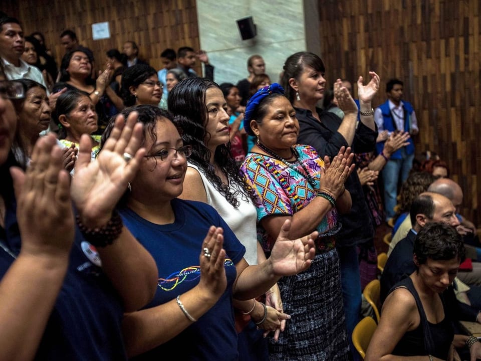 Nobelpreisträgerin Rigoberta Menchú und weitere Zuschauer im Gerichtssaal applaudieren.