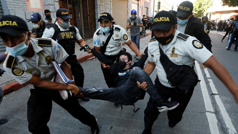 Polizisten tragen einen Demonstranten.
