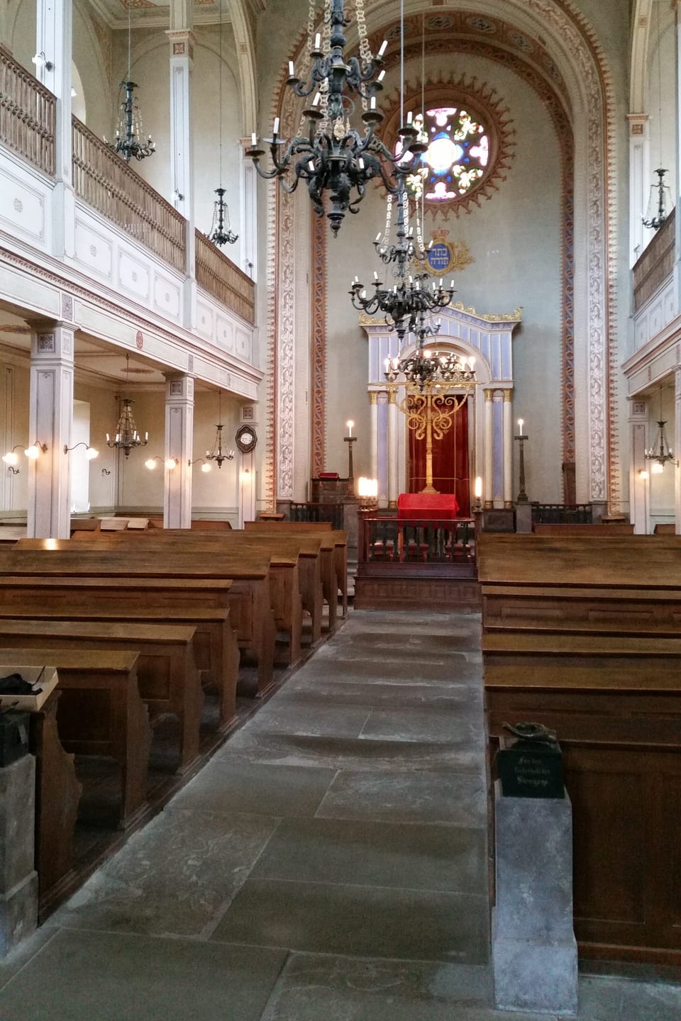 Der Mittelgang der Synagoge mit Holzbänken links und rechts davon.