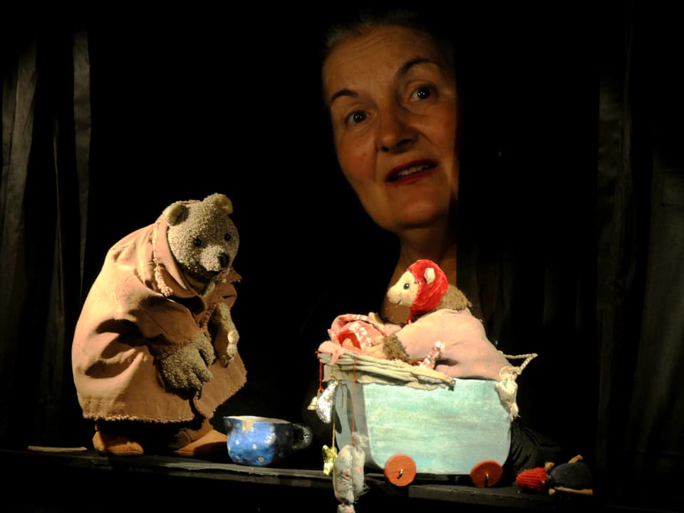 Margrit Gysin spielt mit zwei Figuren - einem Bären und einem Bärenkind im Stubenwagen. 