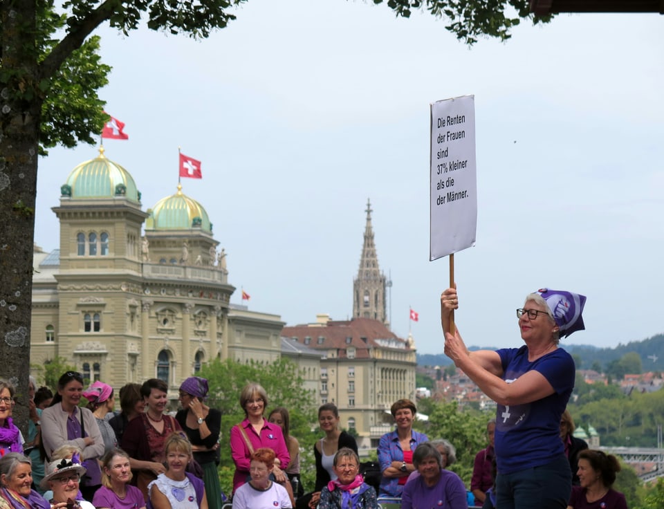 Frau vor Publikum mit Plakat