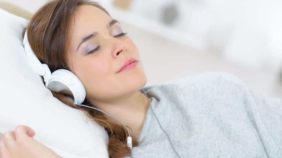 Eine Frau schläft mit Kopfhörern.