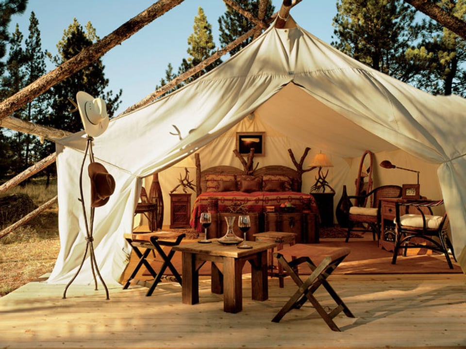 Grosses Zelt mit einem Doppelbett, Tischen und Stühlen.