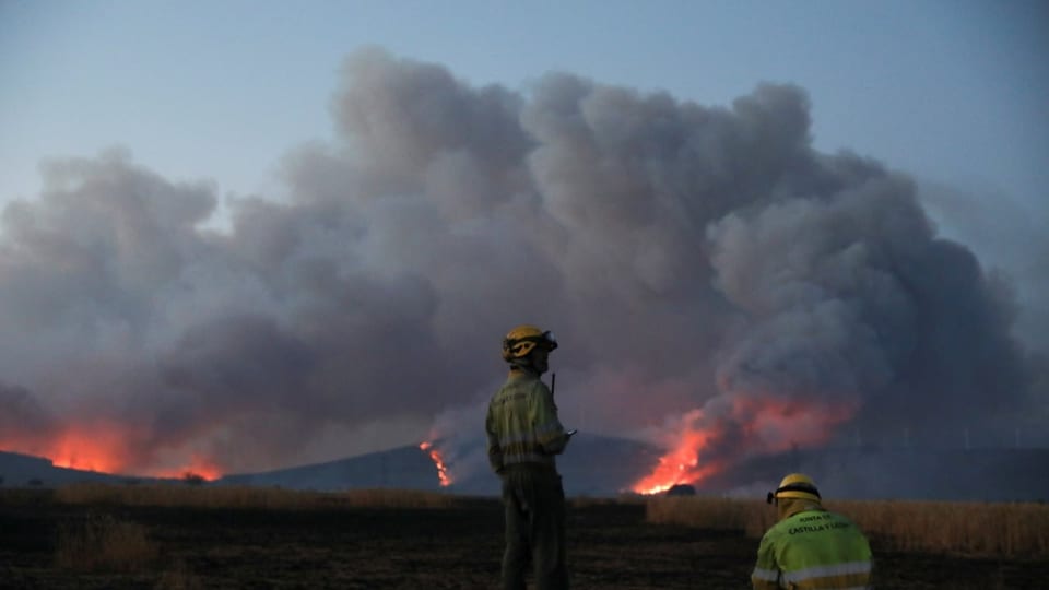 Firefighters stand guard at the fire