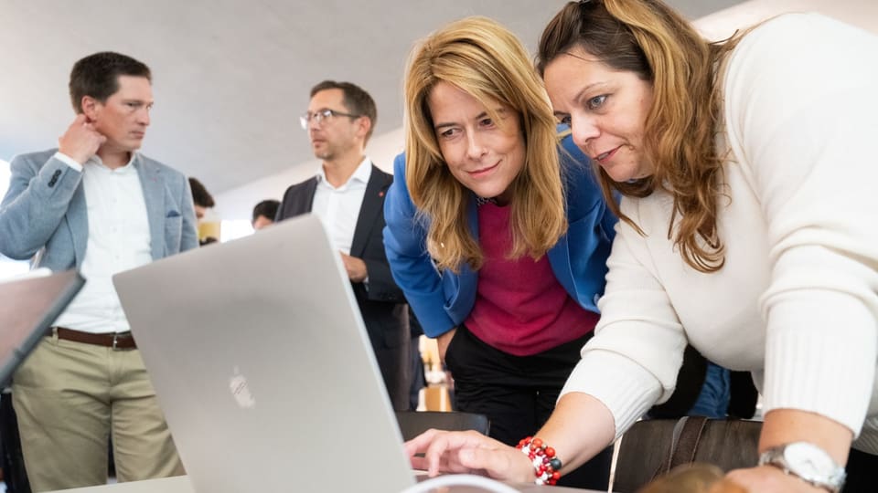 Petra Gössi blickt zusammen mit einer anderen Frau in den Bildschirm eines Laptops.