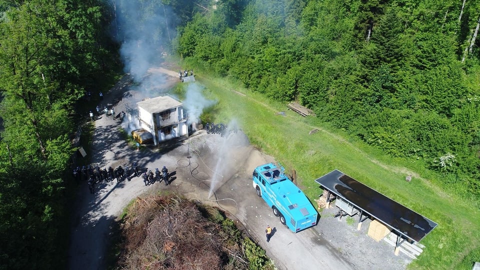 Ein blaues Fahrzeug in der Nähe eines brennenden Gebäudes.