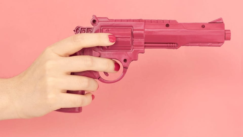eine Frau hält eine rosa Pistole