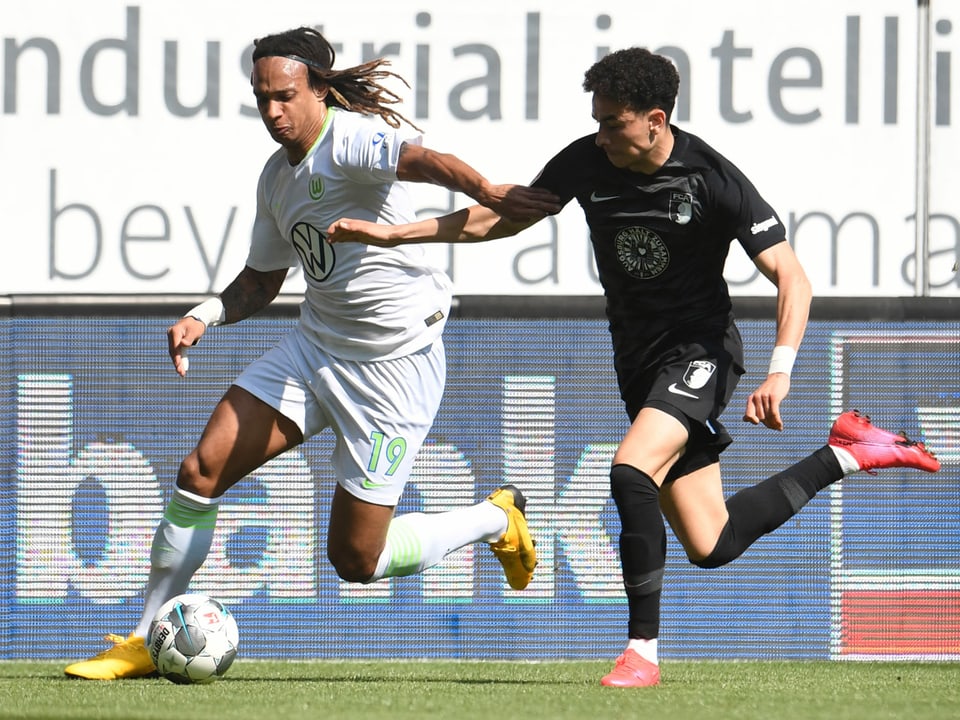 Wolfsburgs Kevin Mbabu setzt sich gegen Augsburgs Ruben Vargas durch.