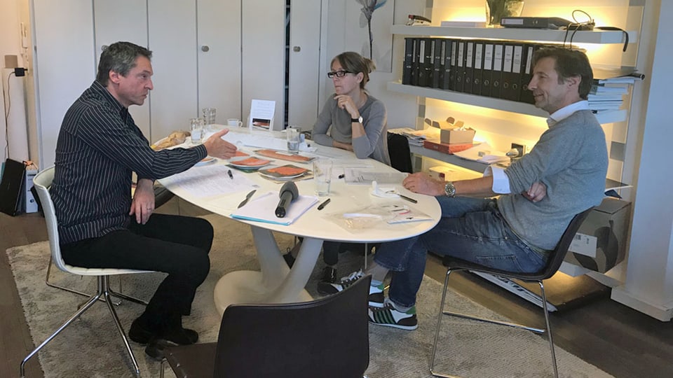 Drei Personen diskutieren an einem Tisch.