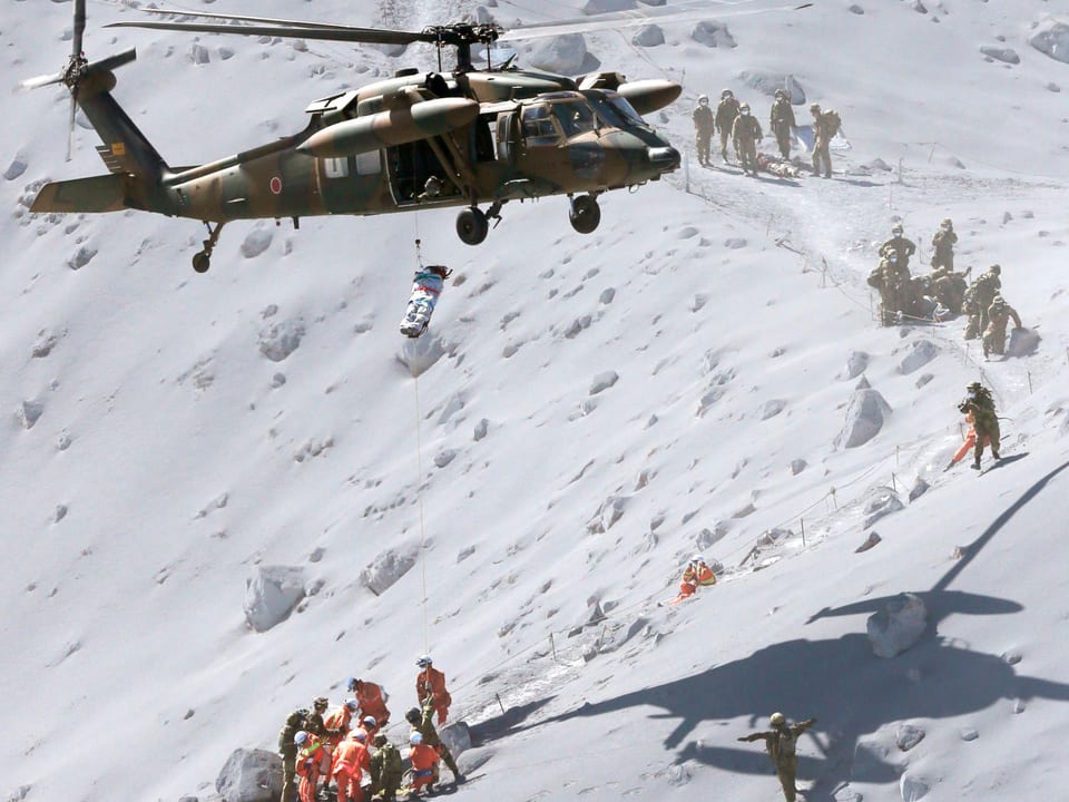 Rettungshelikopter schwebt über dem Vulkan und zieht Verletzten an Bord hoch