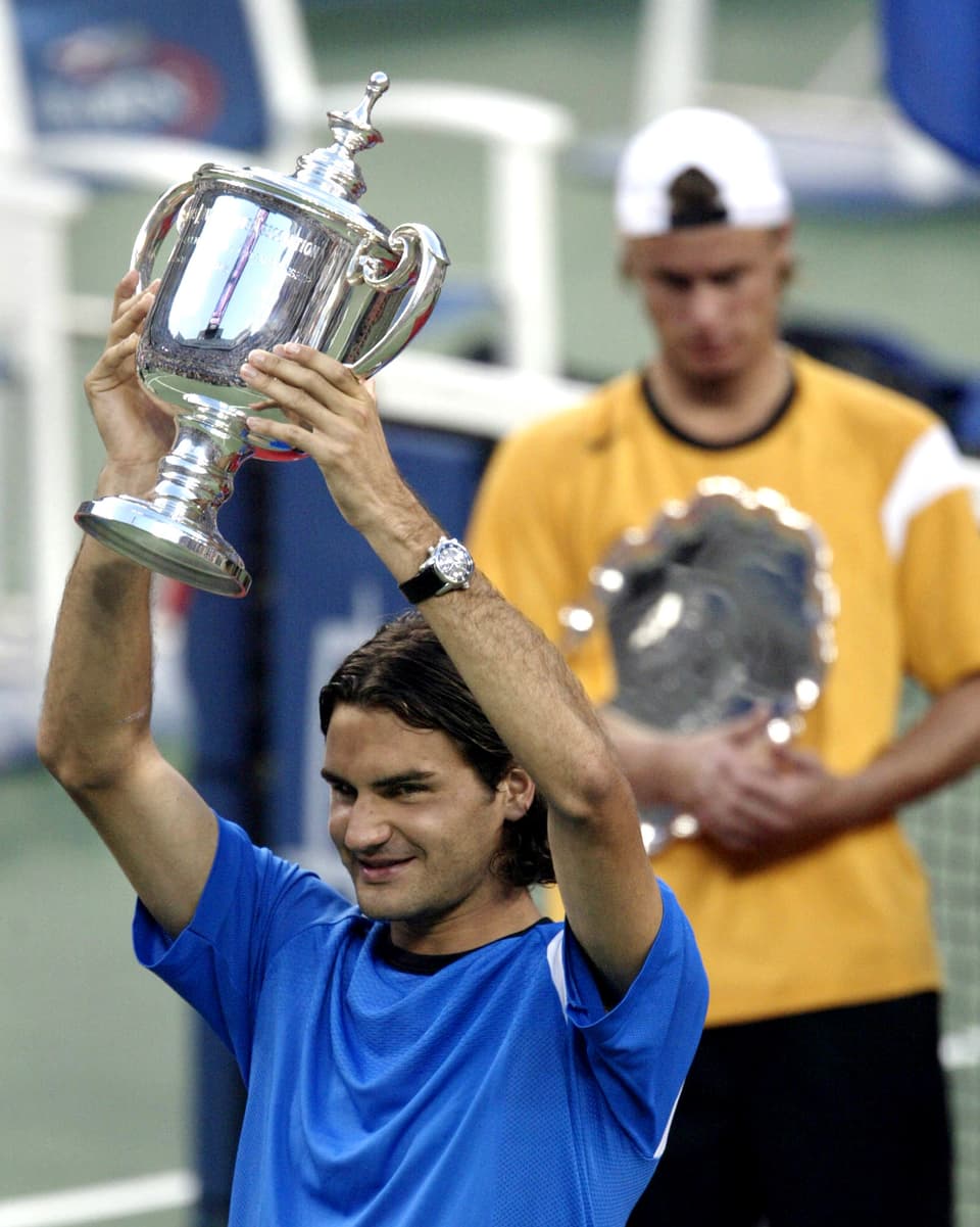 Roger Federer hält eine Trophäe hoch.