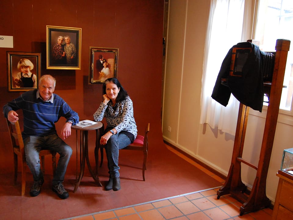 Mann und Frau sitzen in einer Foto-Ausstellung.